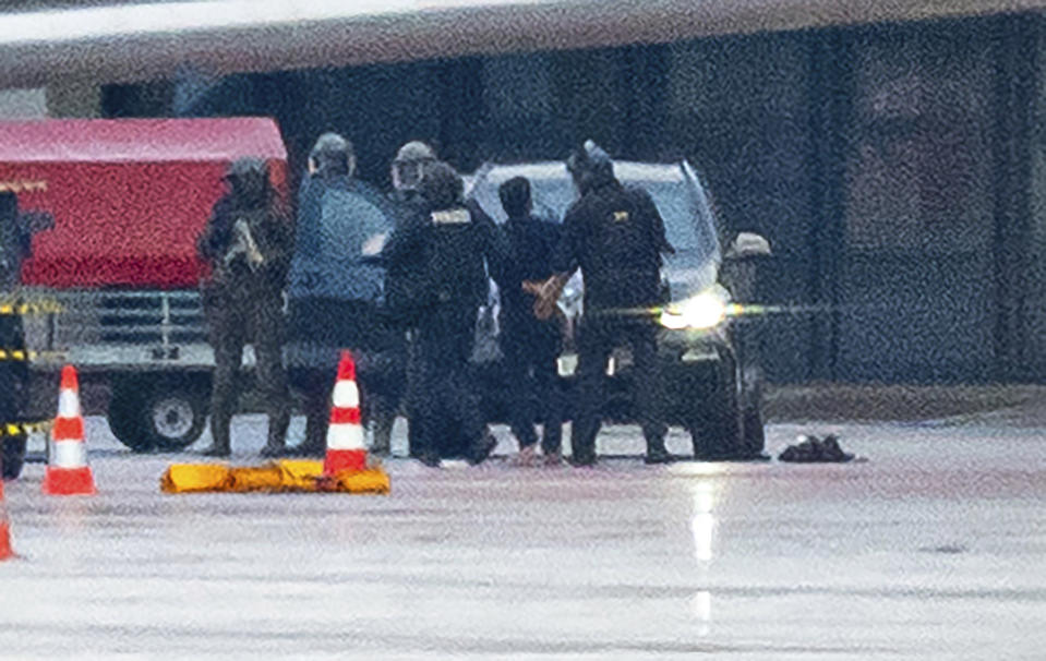 A man is led away by the police at the airport in Hamburg, Germany, Sunday, Nov. 5, 2023. The hostage situation at Hamburg Airport has ended around 18 hours after a man drove his vehicle through the gates of the airport with his 4-year-old daughter inside. Police said Sunday that the man was arrested and the girl appears to be unharmed. (Jonas Walzberg/dpa via AP)