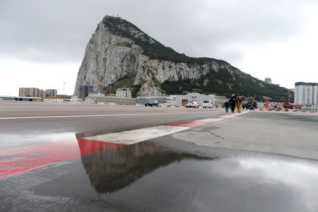 FILE PHOTO: Pedestrians cross the tarmac at Gibraltar International Airport, in front of the Rock, near the border with Spain in the British overseas territory of Gibraltar, historically claimed by Spain, November 25, 2018. REUTERS/Jon Nazca/File Photo