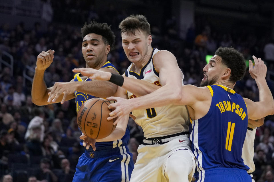 Denver Nuggets guard Christian Braun, center, and Golden State Warriors forward Trayce Jackson-Davis, left, and guard Klay Thompson compete for possession of the ball during the first half of an NBA basketball game Sunday, Feb. 25, 2024, in San Francisco. (AP Photo/Godofredo A. Vásquez)