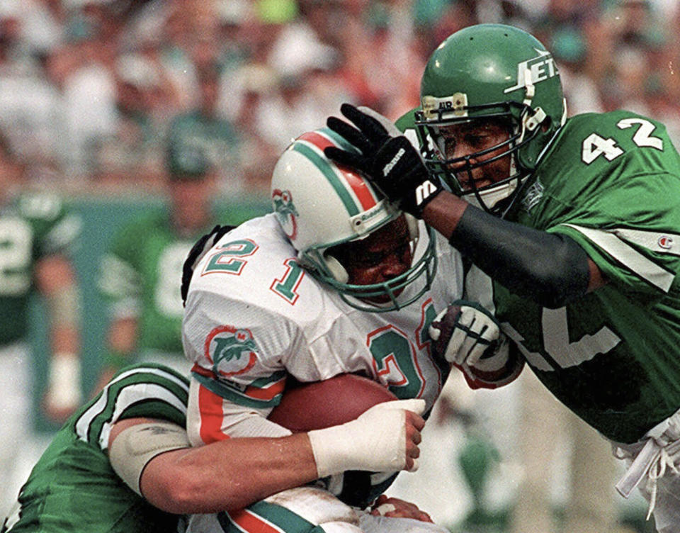 FILE - New York Jets Ronnie Lott (42) and Jeff Lageman, left, bring down Miami Dolphins Mark Higgs (21) during the first half of an NFL football game in Miami, Sept. 12, 1993. Hard-hitting defensive back Lott helped San Francisco win four Super Bowl titles during his 10 seasons with the 49ers. After two seasons with the Raiders, Lott signed with the Jets as a free agent in 1993. (AP Photo/Hans Deryk, File)