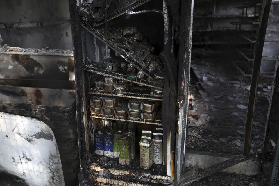 In this Friday, July 27, 2018 photo, yogurts and milks in a burnt refrigerator at a supermarket in Mati, east of Athens. More than 86 people were either killed by the flames or drowned on Monday's wildfire as they tried to flee the fire into the nearby sea, waiting for hours in the water for rescue from local fishermen and private boat owners who saved many. (AP Photo/Thanassis Stavrakis)