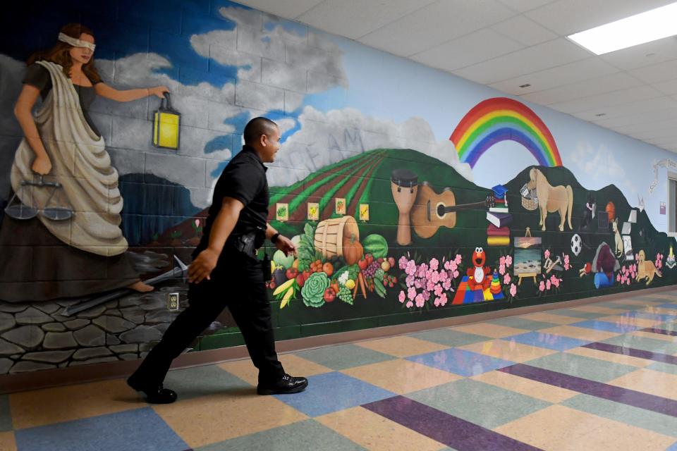 Deputy Probation Officer Oscar Menga walks past a youth mural in the Ventura County Juvenile Facility as local dignitaries visited to celebrate the complex's 20th anniversary in an unincorporated area near El Rio on Tuesday.