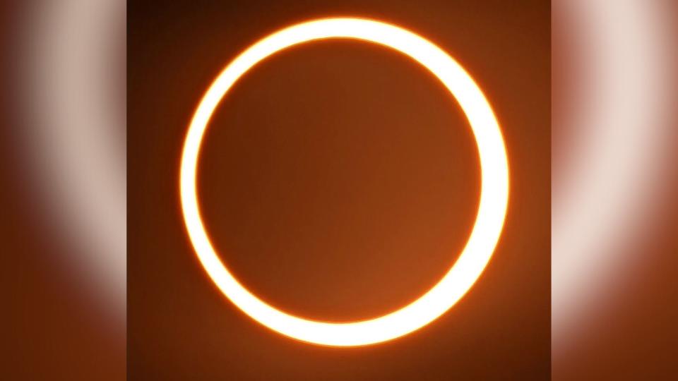 Die ringförmige Sonnenfinsternis erscheint als Feuerring am Himmel. Ein orange leuchtender Kreis.