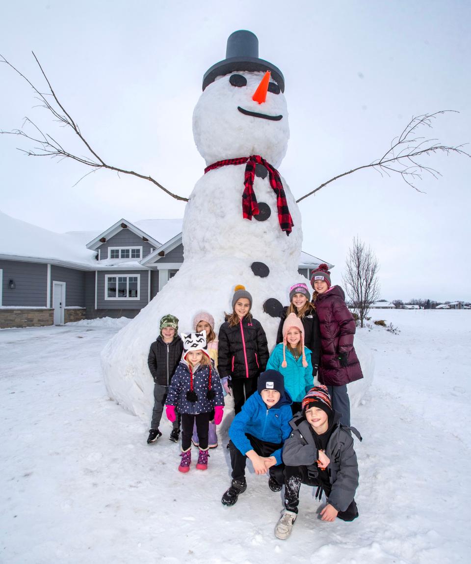 Children of the builders of a 18-foot-tall snowman pose around the creation in the front yard of Jon Voskuil, Monday, January 22, 2024, in Cedar Grove, Wis. The builders, working with Children’s Wisconsin, hope to raise charitable funds for the organization.