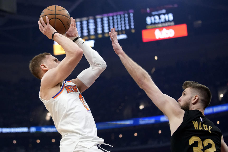 New York Knicks guard Donte DiVincenzo, left, shoots as Cleveland Cavaliers forward Dean Wade (32) defends in the first half of an NBA basketball game, Sunday, March 3, 2024, in Cleveland. (AP Photo/Sue Ogrocki)