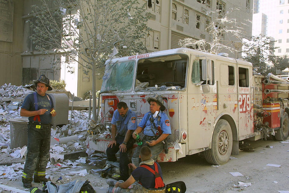 New York City firefighters take a rest at the World Trade Center after two hijacked planes crashed into the Twin Towers September 11, 2001