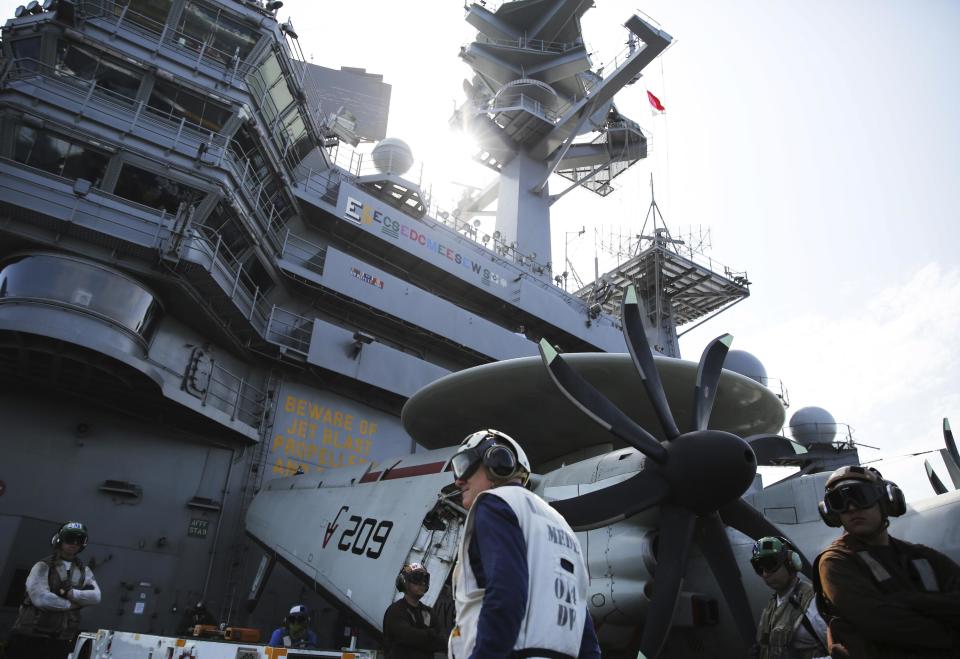 In this Monday, March 20, 2017 photograph, crew man the flight deck of the USS George H.W. Bush as it travels toward the Strait of Hormuz. The arrival of the nuclear-powered aircraft carrier to the Persian Gulf marks the first such deployment under new U.S. President Donald Trump. (AP Photo/Jon Gambrell)