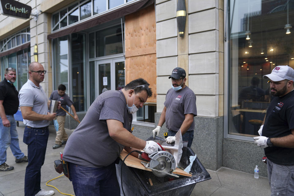 Crews worked to board up the Chipotle on Nicollet Mall, Thursday, Aug. 27, 2020, in Minneapolis, where several businesses were damaged by a group of looters Wednesday night after the suicide of a homicide suspect on the Mall ignited rioting. (Anthony Souffle/Star Tribune via AP)