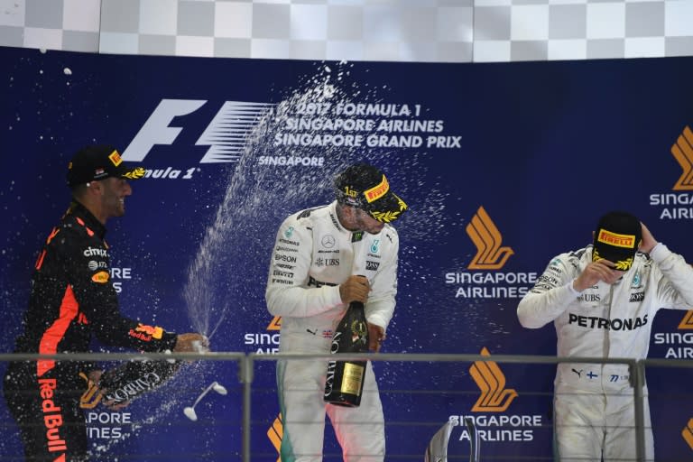 Mercedes' driver Lewis Hamilton (C) celebrates on the podium with second-placed Red Bull's driver Daniel Ricciardo (L) and third-placed Mercedes' driver Valtteri Bottas after the Singapore Grand Prix on September 17, 2017