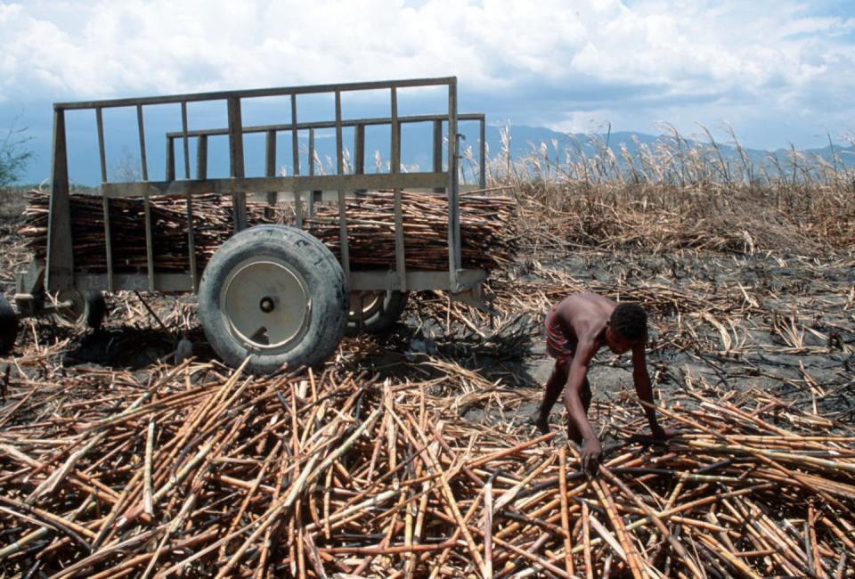 A man stoops over next to a cart.