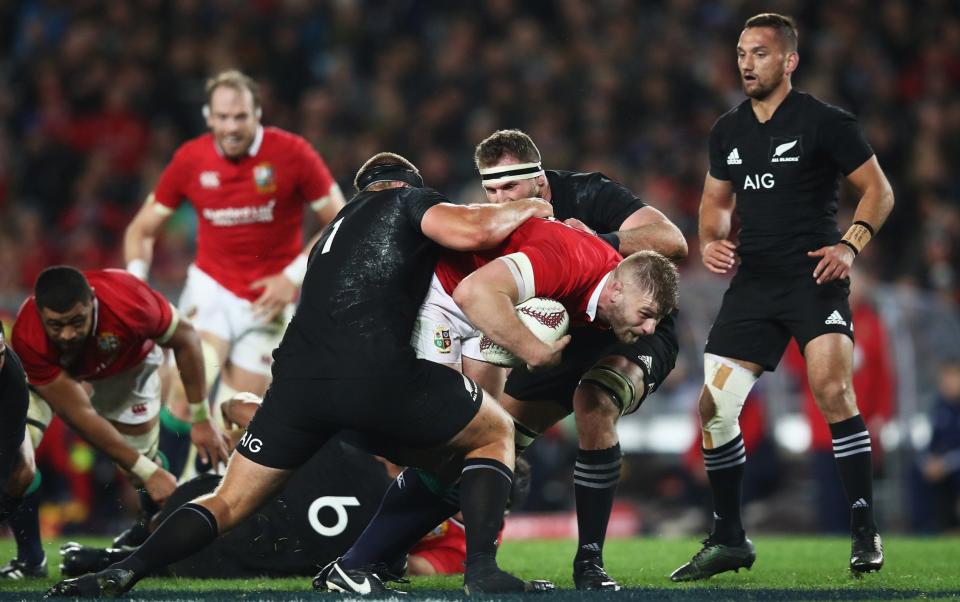 George Kruis of the Lions is tackled by Joe Moody and Kieran Read