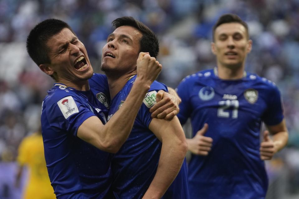 Uzbekistan's Azizbek Turgunboev, right, celebrates with his teammates after scoring the first goal during the Asian Cup Group B soccer match between Australia and Uzbekistan at Al Janoub Stadium in Doha, Qatar, Tuesday, Jan. 23, 2024. (AP Photo/Thanassis Stavrakis)