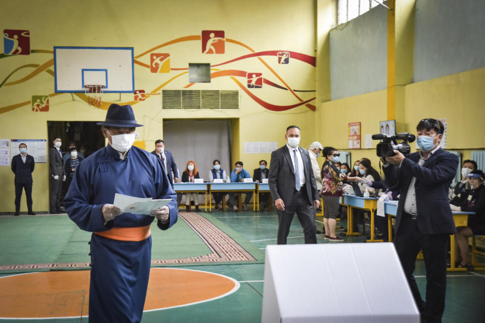 In this photo released by Xinhua News Agency, Mongolian Prime Minister Ukhnaa Khurelsukh at left prepare to cast his vote at a polling station in Ulaanbaatar, Mongolia, on Wednesday, June 24, 2020. Mongolians were voting in parliamentary elections Wednesday across the vast, lightly populated country, a U.S. ally squeezed between authoritarian governments in China and Russia. The polls are being held amid considerable success in the country's fight against the coronavirus, with just 215 cases of COVID-19 recorded. All of them have been imported and no one has died. (Chadraabal/Xinhua via AP)