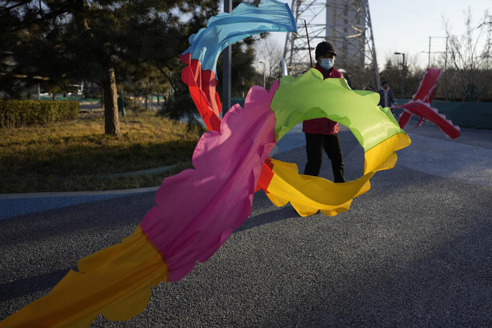 A resident wearing a mask exercises with a colored ribbon in Beijing, China, Tuesday, Jan. 11, 2022. The Chinese capital is on high alert ahead of the Winter Olympics as China locks down a third city elsewhere for COVID-19 outbreak. (AP Photo/Ng Han Guan)