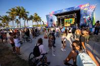 People walk by a concert for Art on the Drive, a Carnaval Miami event, at Lummus Park during Spring Break in Miami Beach, Florida, on Saturday, March 18, 2023.