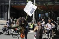 A protester holds a sign critical of Seattle Mayor Jenny Durkan and the Seattle Police Department as they block a street in front of Seattle City Hall, Monday, July 13, 2020, following a news conference. Police Chief Carmen Best and Durkan were critical of a plan backed by several city council members that seeks to cut the police department's budget by 50 percent. (AP Photo/Ted S. Warren)