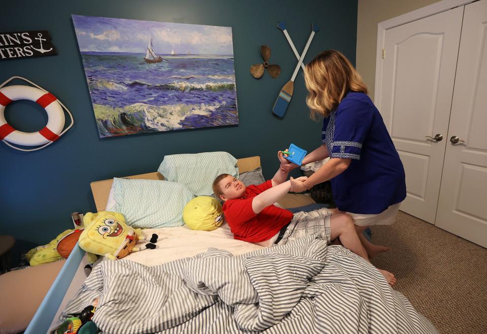 Annette Maughan pulls her 20-year-old son Glenn Maughan, nicknamed Bug, out of bed in Manchester, Md., on Friday, July 7, 2023. Bug has KBG syndrome. He currently experiences one to three seizures a day. | Kristin Murphy, Deseret News