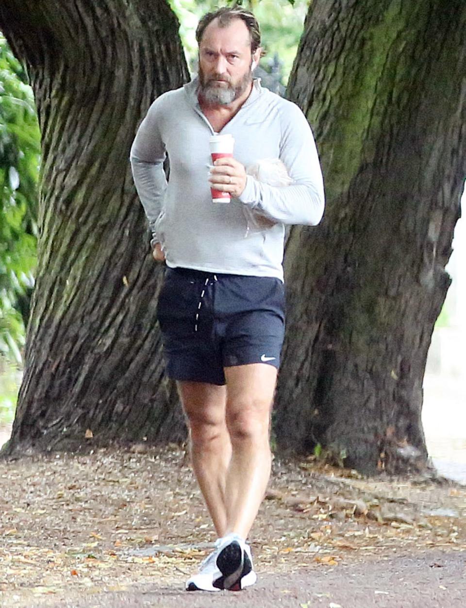 <p>Jude Law returns from his solo Wednesday morning run in a London park with a coffee.</p>