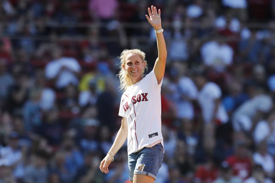 Retired soccer player and Olympic gold medal champion Kristine Lilly waves to the crowd before throwing out the ceremonial first pitch before a baseball game between the Boston Red Sox and the New York Yankees, Saturday, July 24, 2021, in Boston. (AP Photo/Michael Dwyer)