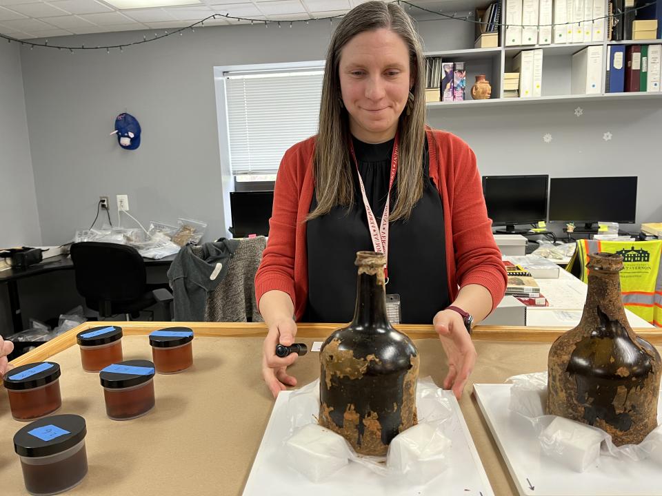 Lily Carhart, curator of preservation collections at George Washington's Mount Vernon, shows historic bottles recently found buried there. The liquid and cherries inside were removed and placed in small containers, at left. (Michael E. Ruane/The Washington Post)