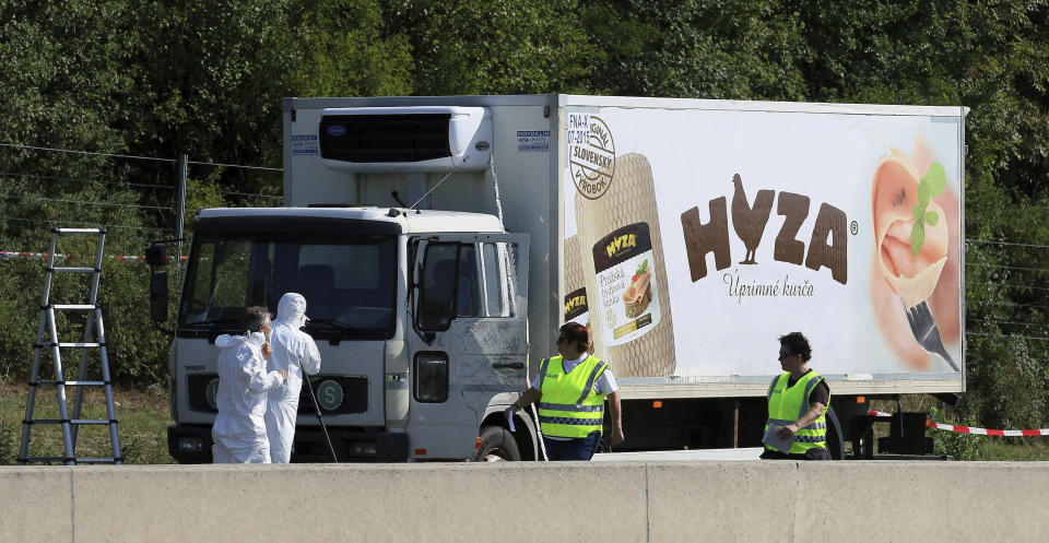 FILE - In this Thursday, Aug. 27, 2015 file photo, investigators stand near an abandoned truck on the shoulder of Highway A4 near Parndorf, Austria, south of Vienna. A Hungarian court has extended the prison sentences of four human traffickers convicted last year for their roles in a 2015 in which 71 migrants suffocated to death in the back of a refrigerated truck found on a highway in Austria. (AP Photo/Ronald Zak, file)