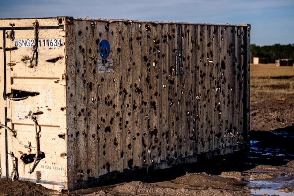 A cargo container is covered with bullet holes