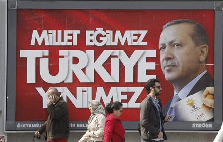 People walk past a poster for Turkey's Prime Minister Tayyip Erdogan's election campaign in Istanbul March 27, 2014. REUTERS/Osman Orsal