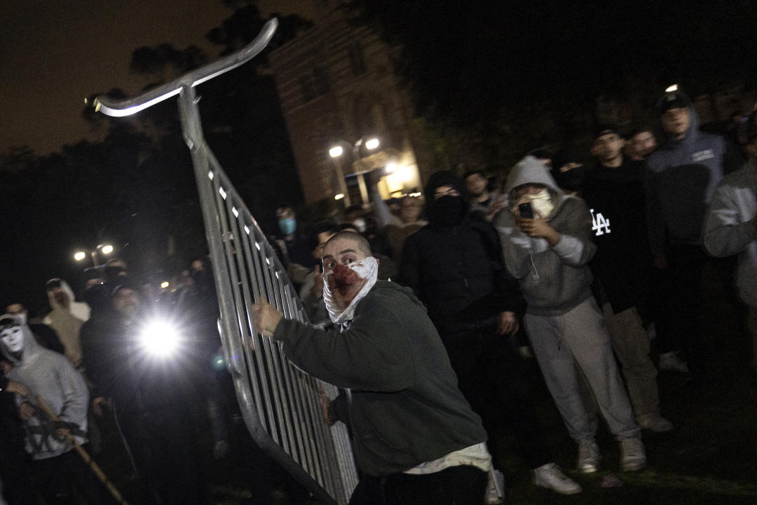 A counterprotester throws a barricade at pro-Palestinian protesters next to their encampment on UCLA's campus.