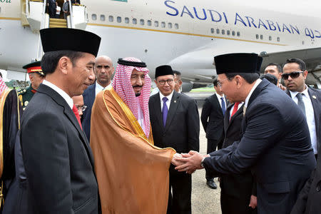 Indonesia President Joko Widodo (L) stands as Saudi Arabia's King Salman (C) shakes hands with Jakarta Governor Basuki Tjahaja Purnama at Halim Perdanakusuma airport in Jakarta, Indonesia March 1, 2017 in this photo taken by Presidential Palace Photographer. Presidential Palace Photographer/Agus Suparto/Handout via REUTERS