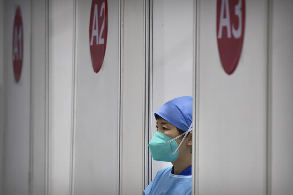 A medical worker wearing protective equipment waits for patients at a coronavirus vaccination facility in Beijing, Friday, Jan. 15, 2021. A city in northern China is building a 3,000-unit quarantine facility to deal with an anticipated overflow of patients as COVID-19 cases rise ahead of the Lunar New Year travel rush. (AP Photo/Mark Schiefelbein)