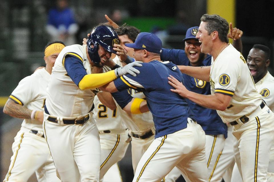 Victor Caratini (left) is mobbed by teammates after delivering a game-winning, two-run single against the Dodgers in the 11th inning Tuesday night at American Family Field.