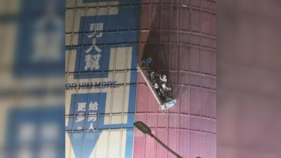 昨深夜微風南京百貨有3名工人受困高樓外牆洗車平台，消防人員出動雲梯車救援。（翻攝自爆料公社）
