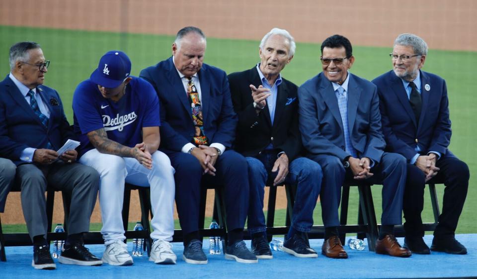 Fernando Valenzuela sits on a podium next to Jaime Jarrín, Julio Urías, Mike Scioscia, Sandy Koufax and Charlie Steiner.