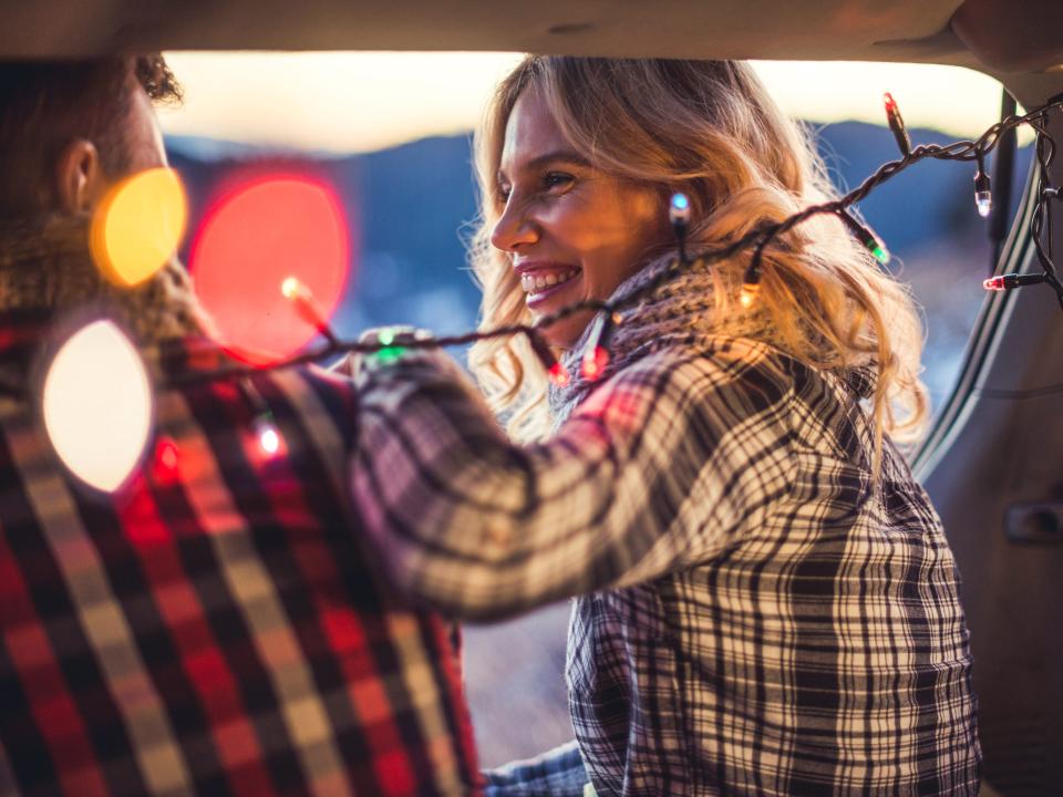 Couple in love sitting in a car trunk and watching the sunrise.