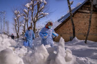 Fozia, right and Tasleema, Kashmiri healthcare workers, carry vaccines as they walk on a snow covered road during a COVID-19 vaccination drive in Budgam, southwest of Srinagar, Indian controlled Kashmir, Jan. 11, 2022. (AP Photo/Dar Yasin)