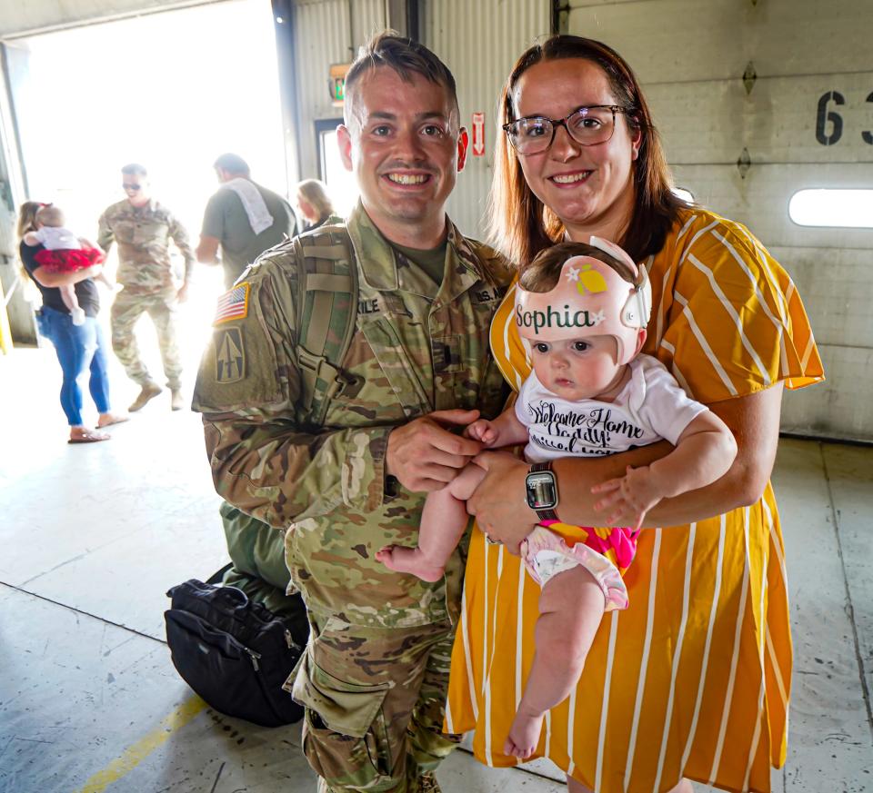 Lt. Eric and Anna Kile hold their daughter Sophia after Lt. Kile, who is with the Indiana National Guard,163rd Field Artillery Regiment, headquartered in Evansville, deplaned upon returning home from deployment in Iraq on Thursday, Aug.3, 2023, near the Indianapolis International Airport.