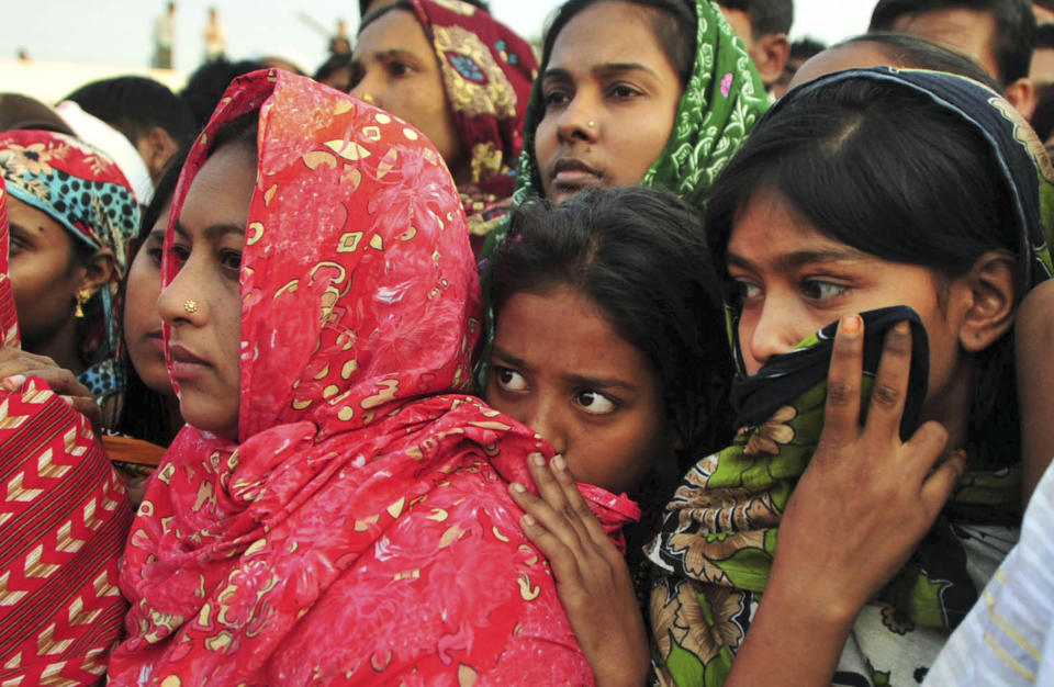 Bangladeshi women watch the bodies of some of the victims of Saturday's fire in a garment factory being prepared to be buried, in Dhaka, Bangladesh, Tuesday, Nov. 27, 2012. Bangladesh held a day of mourning Tuesday for the 112 people killed at the factory, and labor groups planned more protests to demand better worker safety in an industry notorious for operating in firetraps. (AP Photo/Khurshed Rinku)