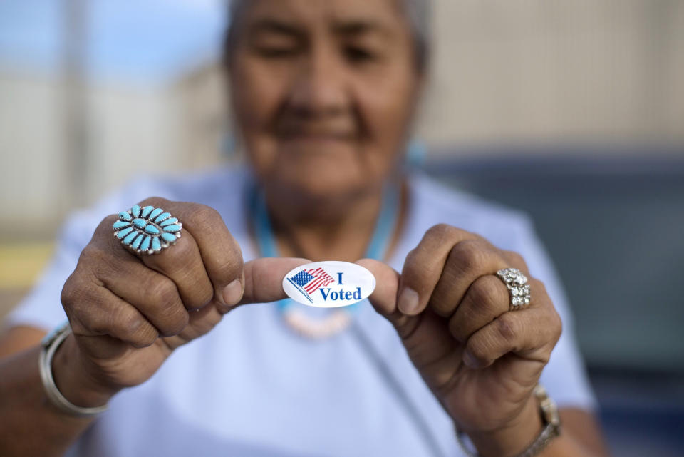 FILE - In this Aug. 28, 2018 file photo, Mildred James of Sanders, Ariz., shows off her "I Voted" sticker as she waits for results of the Navajo Nation presidential primary election to be revealed in Window Rock, Ariz., different approaches to precinct voting in the 2020 general election. Voters in Apache County had to cast ballots at the polling location they were assigned. People registered in Navajo County could vote anywhere in the county. Coconino County used a hybrid model. The Navajo Nation has long argued the approach is inconsistent and confusing, leading to ballots being rejected and tribal members being denied the same opportunity to vote as others in Arizona. The U.S. Supreme Court disagreed on Thursday, July 1, 2021, in a broader case over Arizona voting regulations, upholding a prohibition on counting ballots cast in the wrong precinct and returning early ballots for another person. (AP Photo/Cayla Nimmo, File)