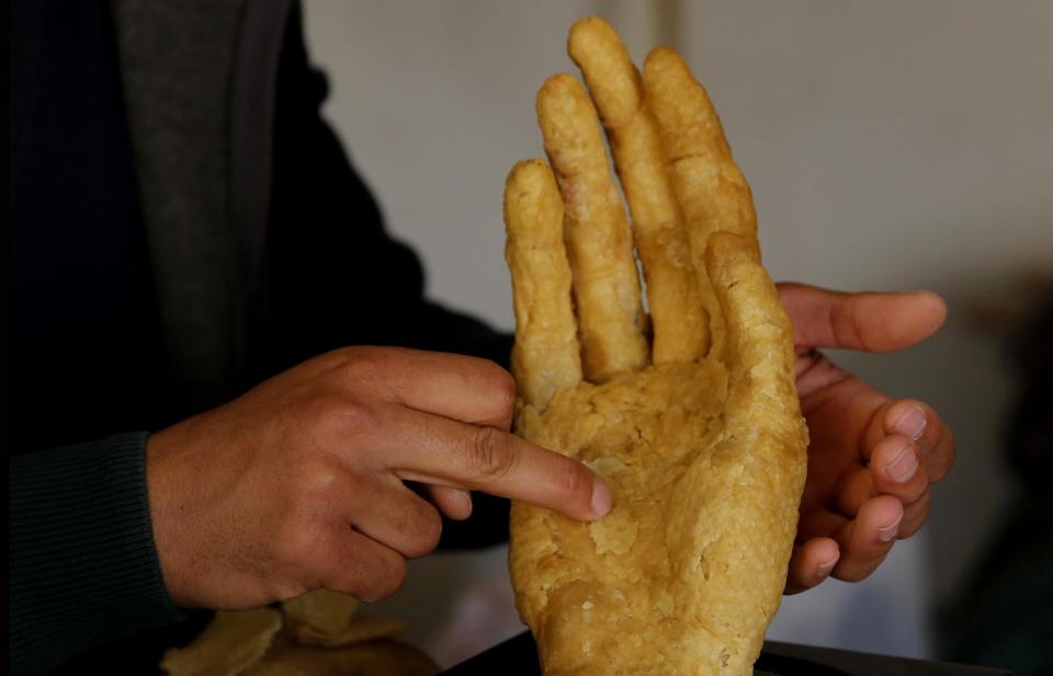 In this Tuesday March 14, 2017 photo, Palestinian artist Mohammed Abu Hashish, 28, shapes a hand from honeycomb in his small workshop in a refugee camp in the central Gaza Strip. The artist is crafting art out of honeycomb to draw attention to Palestinians who lost limbs in fighting with Israel. (AP Photo/Hatem Moussa)