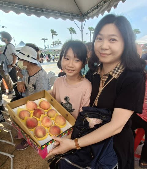 謝小姐和女兒以三千元拍下一盒得獎的水蜜桃，母女展示勝利品，樂不可支。（記者黃福鎮攝）
