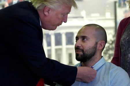 U.S. President Donald Trump awards a Purple Heart to Army Sgt First Class Alvaro Barrientos at Walter Reed National Military Medical Center in Bethesda, Maryland, U.S., April 22, 2017. REUTERS/Yuri Gripas