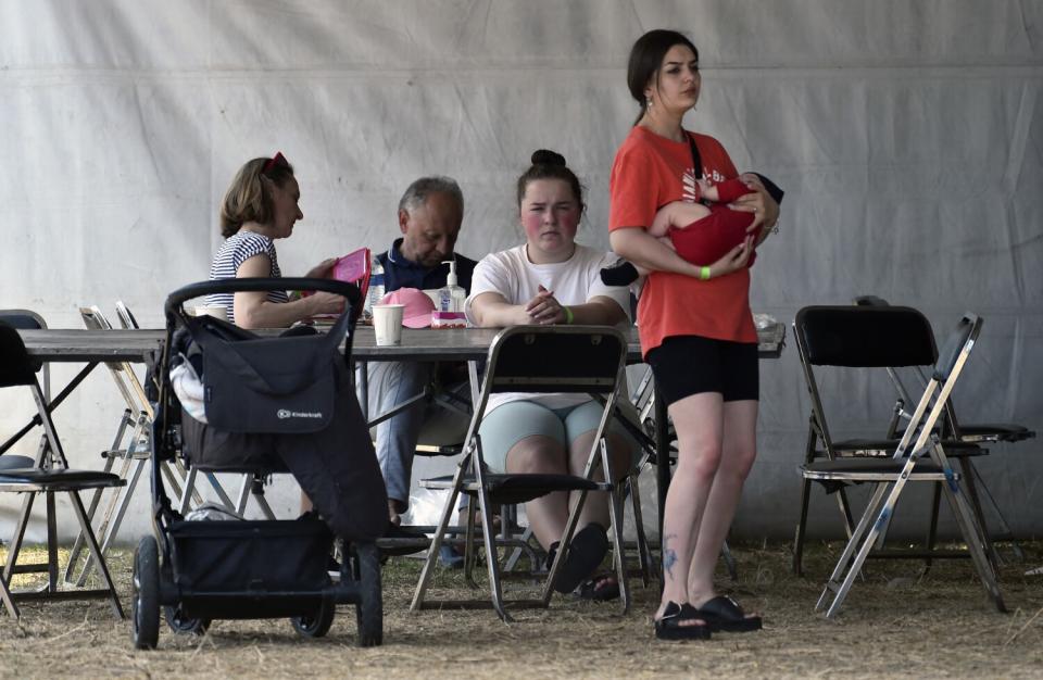 A standing woman holds an infant while other people sit