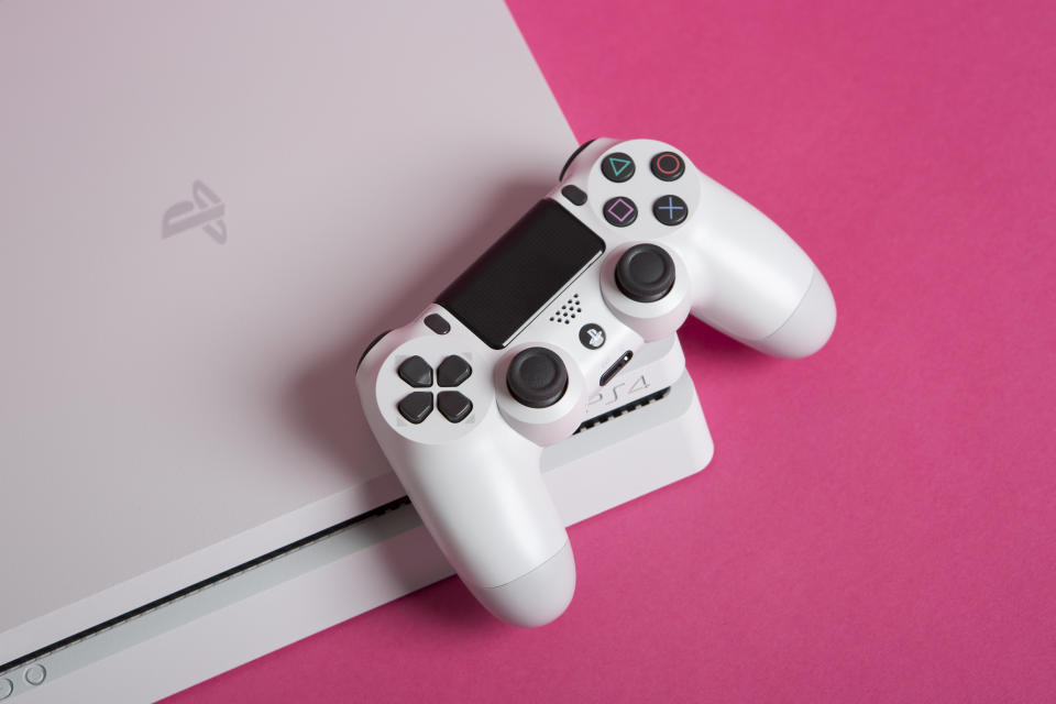 Turku, Finland - March 07, 2018: PlayStation 4 (PS4) with a DualShock controller. The PS4 is a video gaming console produced by Sony Computer Entertainment. Sony Playstation 4 Gaming Console With Controller. White PS4 on pink background.