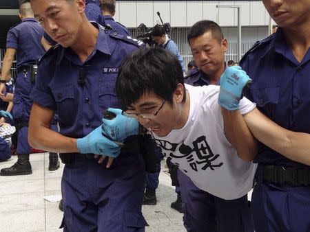 Alex Chow, secretary-general of the Hong Kong Federation of Students, reacts as he is taken away by police after storming into government headquarters in Hong Kong September 27, 2014. REUTERS/Donny Kwok