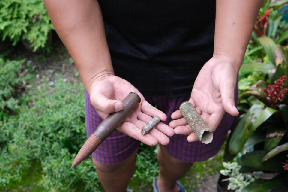 An Angami Naga boy Viketouzo Miachieo, 22, displays ammunition from World War II that he found a few years ago while cleaning the area beside his house in Kohima village, in the northeastern Indian state of Nagaland, Tuesday, Aug. 18, 2020. Miachieo fitted the RG 1942 20mm cartridge, left, with a wooden carving on top to make it look like an unused shell. Between April and June 1944, Japanese and British Commonwealth forces fought across Kohima and the area around it in a battle that has been chosen as Britain's greatest battle by the National Army Museum, along with their battle in neighboring Imphal region. (AP Photo/Yirmiyan Arthur)