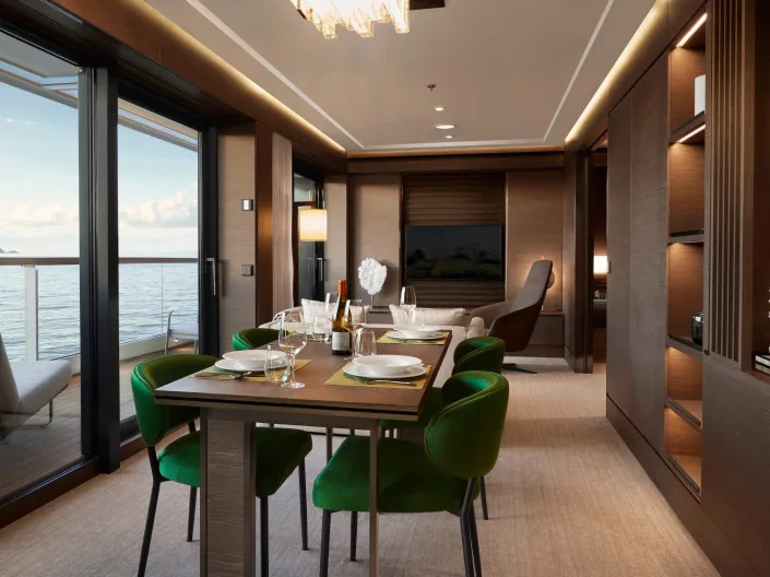 The grand suite with a set dining table, TV, balcony facing the ocean.