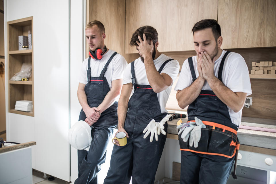 Group of young construction workers having problems during home renovation process.