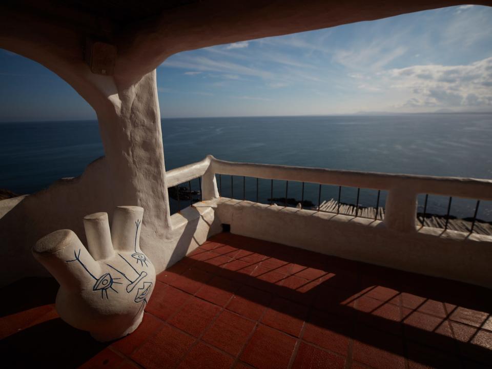 White sculpture artwork on tiled floor on a balcony overlooking the ocean.