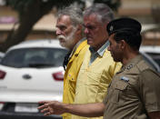 Jim Fitton, left, and Volker Waldmann, center, are handcuffed as they walk outside a courtroom escorted in Baghdad, Iraq, Sunday, May 22, 2022. Waldmann and Fitton have been accused of smuggling ancient shards out of Iraq. (AP Photo/Hadi Mizban)