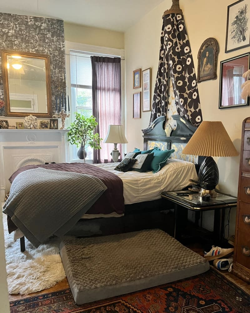 Dog bed next to regular bed with Marimekko fabric draped above in bedroom with light colored walls.